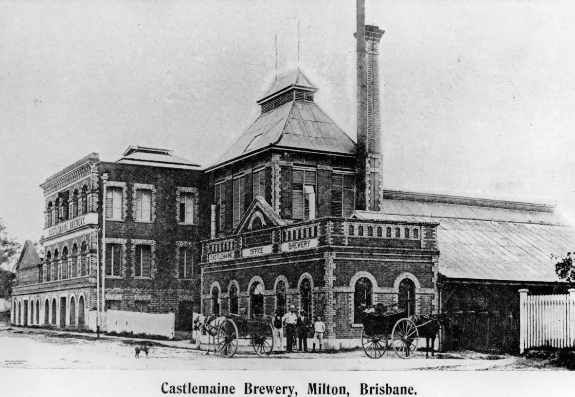Exterior view from the street of the brick edifice of the Castlemaine Brewery. The facade with brick, arched windows is featured. A group of people pose on the corner with some horse-drawn buggies.