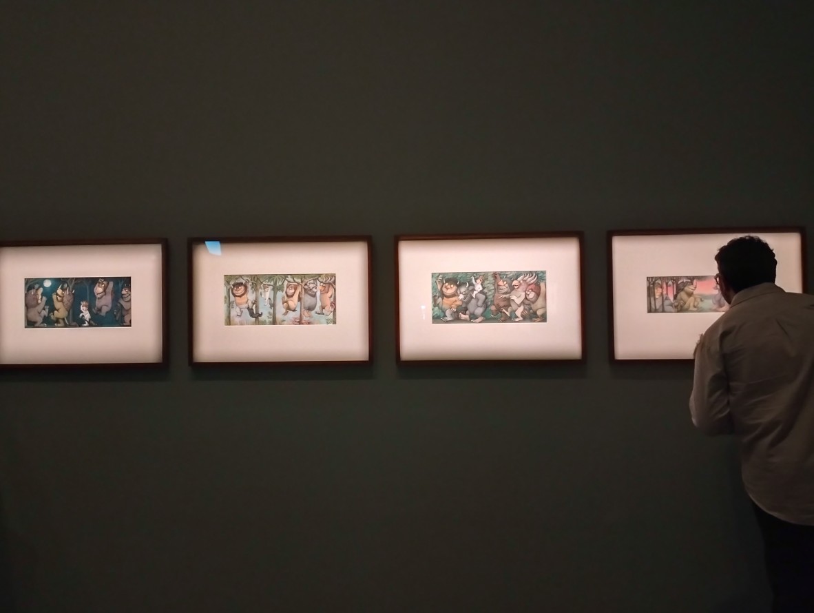 Darkened room with four framed photographs with silhouette of person on right hand side.