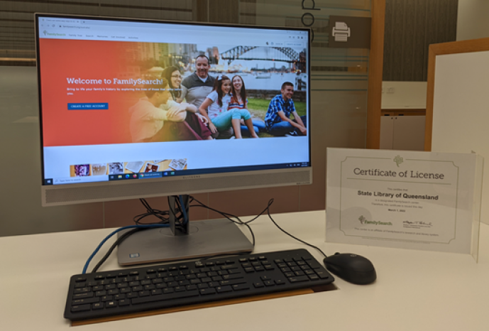 Computer screen displaying home page for FamilySearch with affliate certificate on table on right