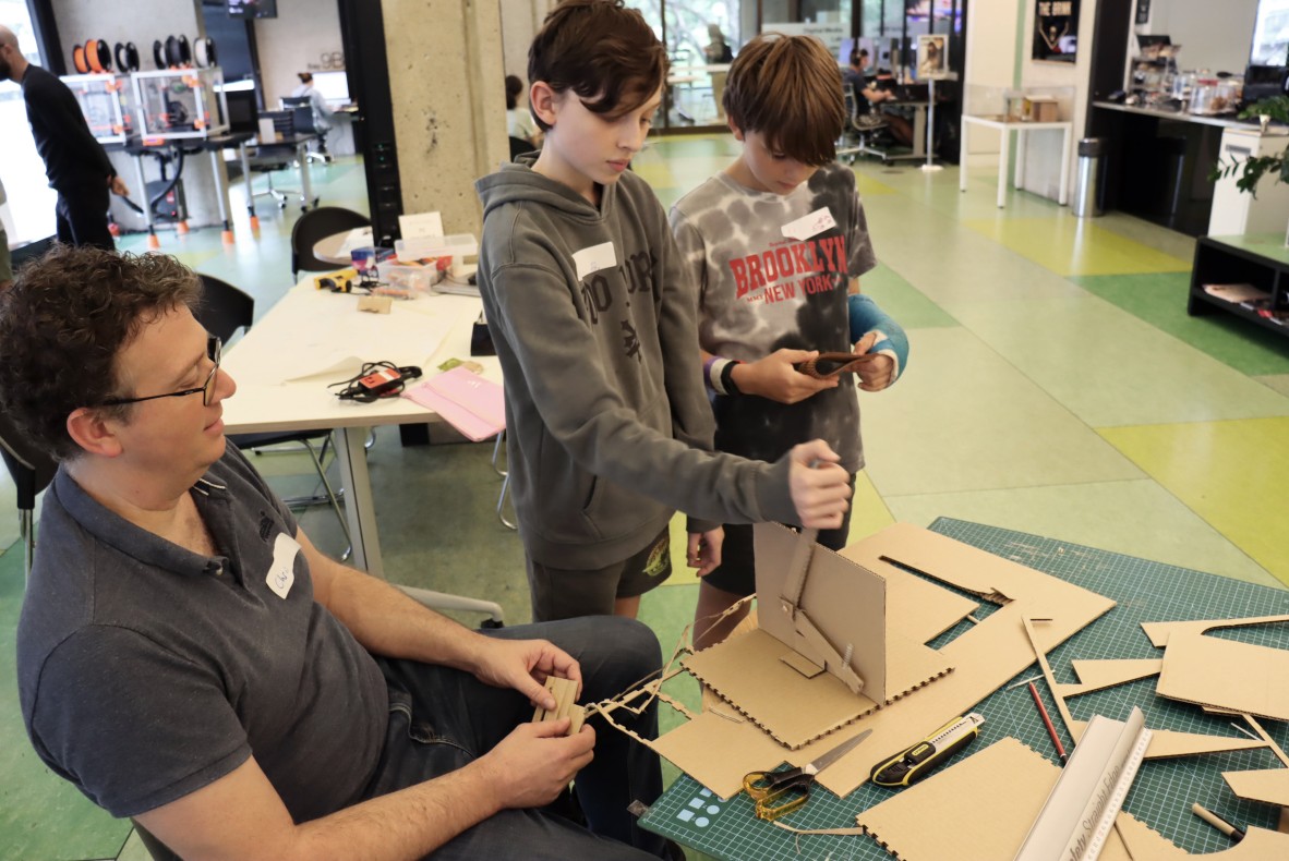 Three people creating cardboard DIY leaver for games