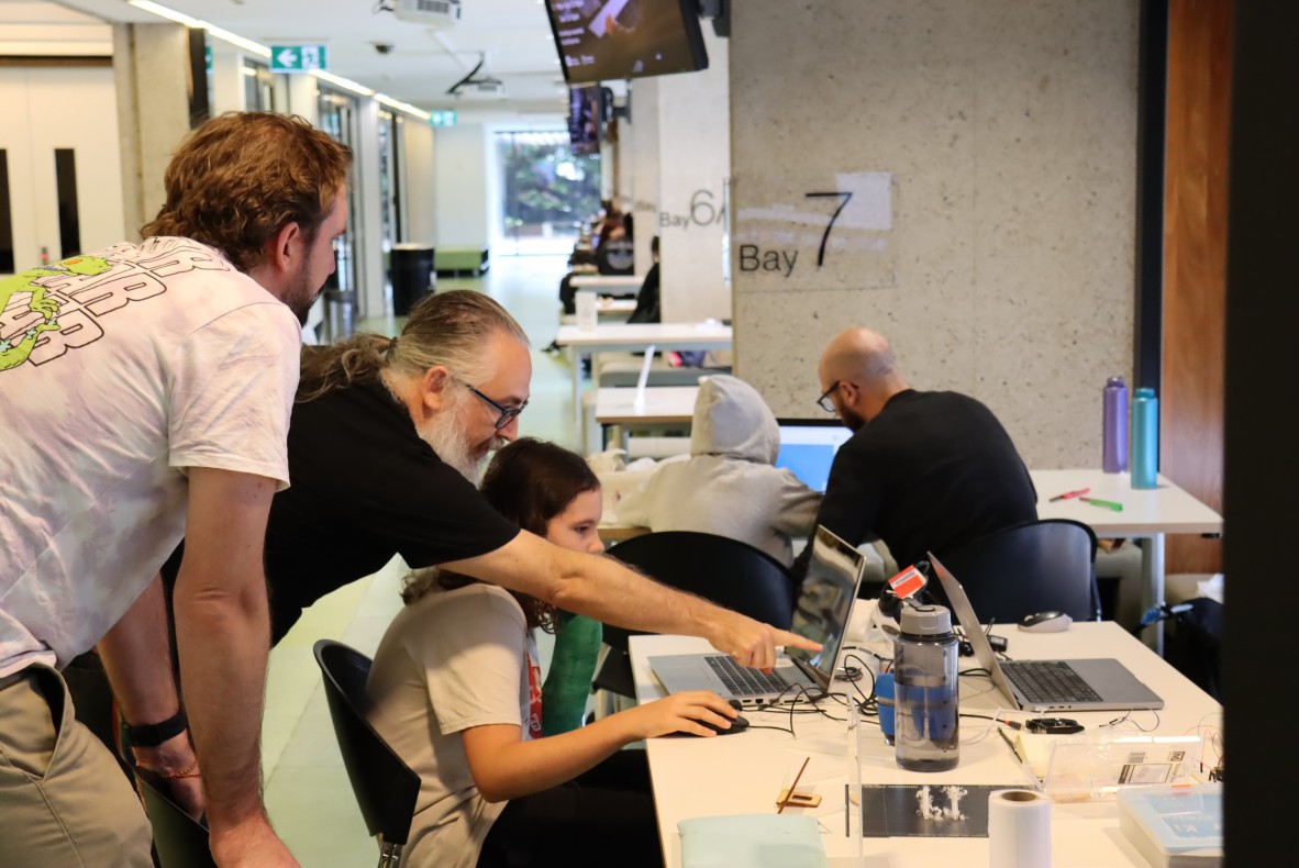 Person teaching child and father how to use TinkerCad