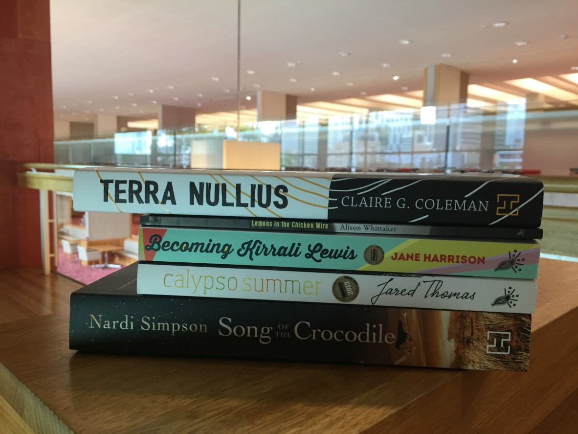 A book stack on a shelf in State Library containing Terra Nullius, Lemons in the chicken wire, Becoming Kirrali Lewis, Calypson summer, and Song of the crocodile
