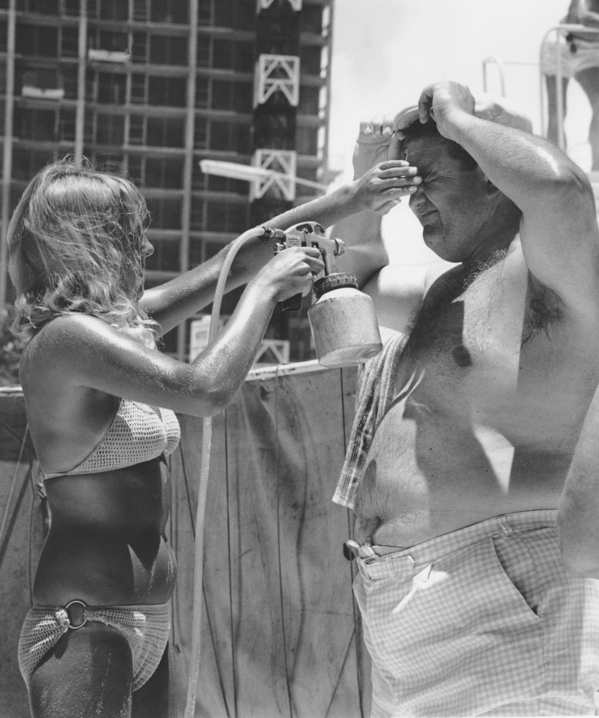 Beachgoer being sprayed with Mutton bird tanning oil Surfers Paradise c 1960s