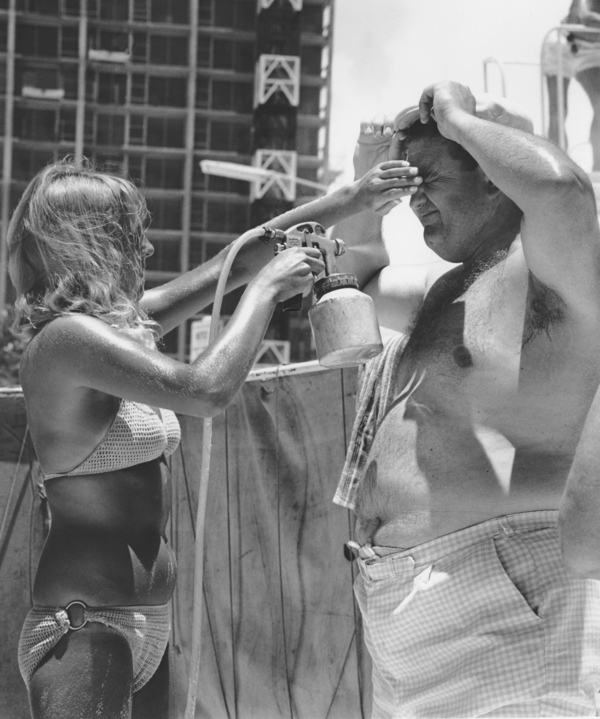 Beachgoer being sprayed with Mutton bird tanning oil, Surfers Paradise, c. 1960s