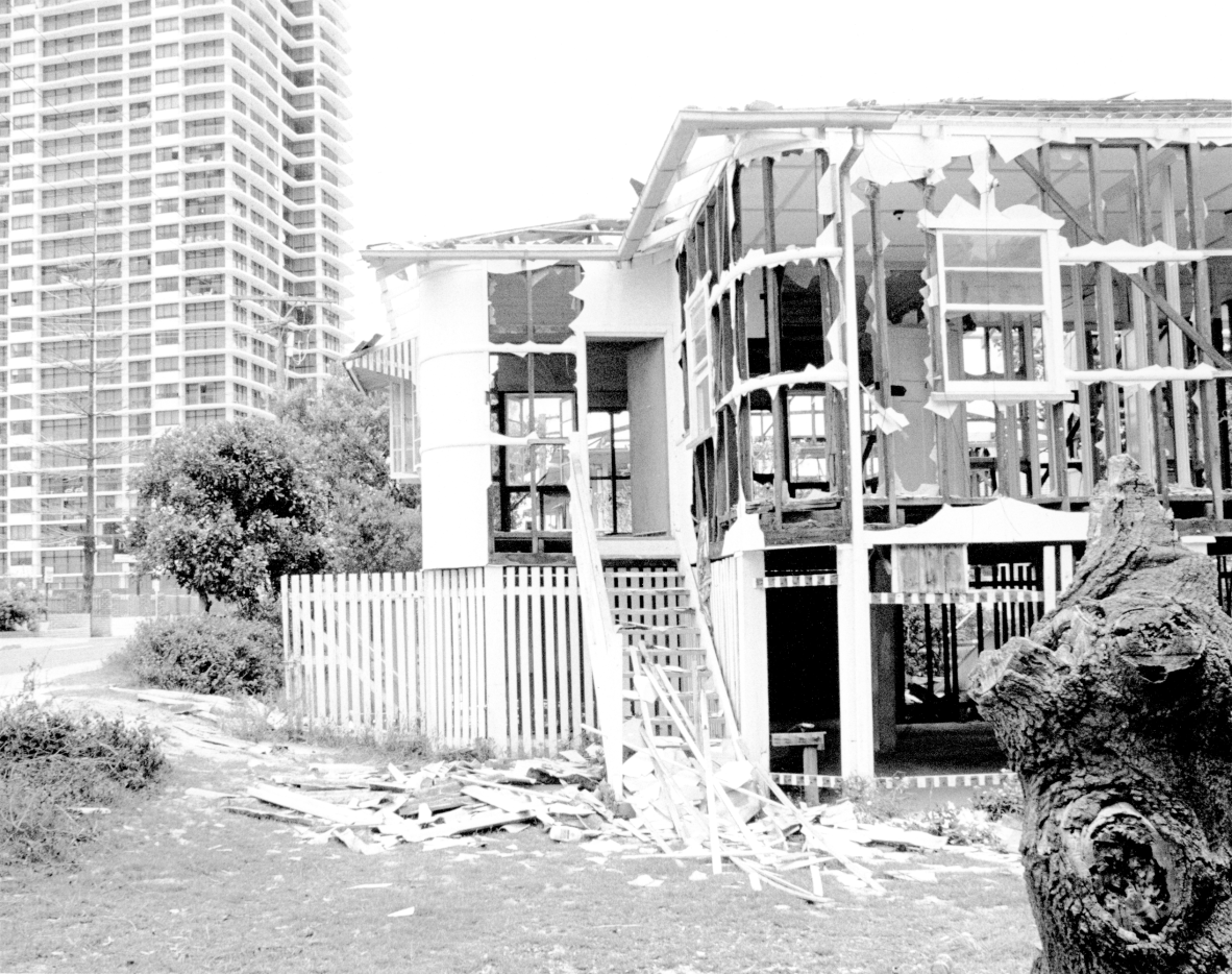 Demolished frame of a house in Surfer Paradise. A high-rise appartment block is visible behind. ca.1970s