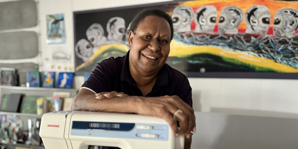 Woman standing at sewing machine smiling