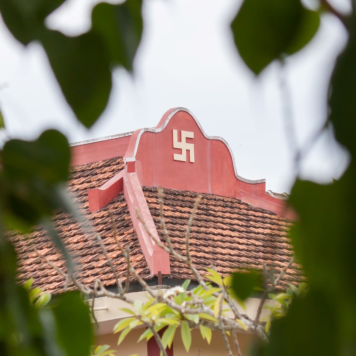 Swastika symbol on temple roof, viewed through trees