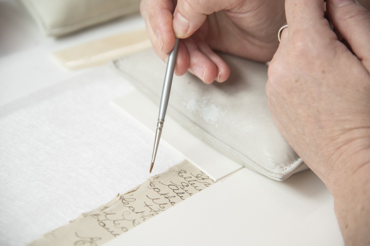 A conservator working on a torn paper fragment