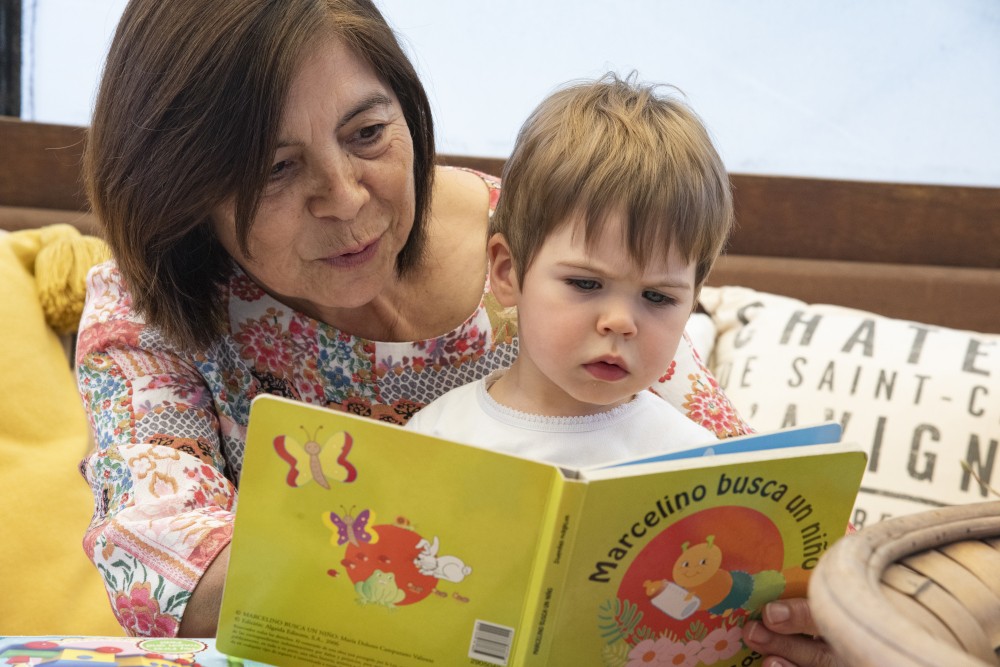 A woman and a small child are looking at a book. The title of the book is in Spanish.