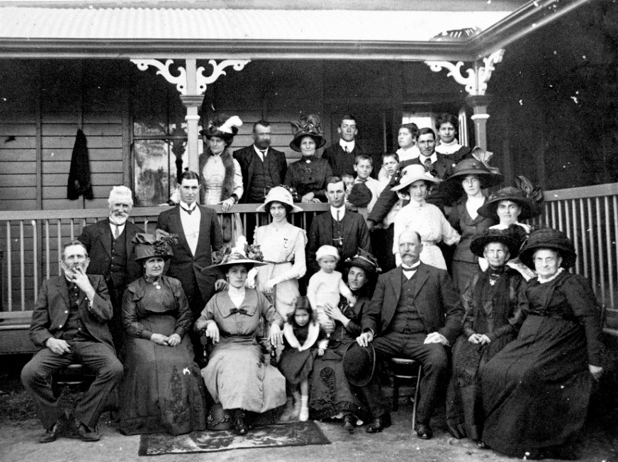 A black and white photograph of a family group sitting out the front of a house