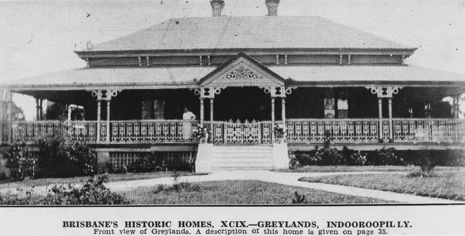 A black and white photograph of a house with a two tiered roof and lattice work