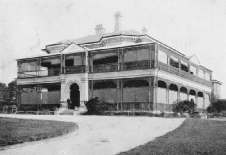 A black and white photograph of a two storey house and driveway