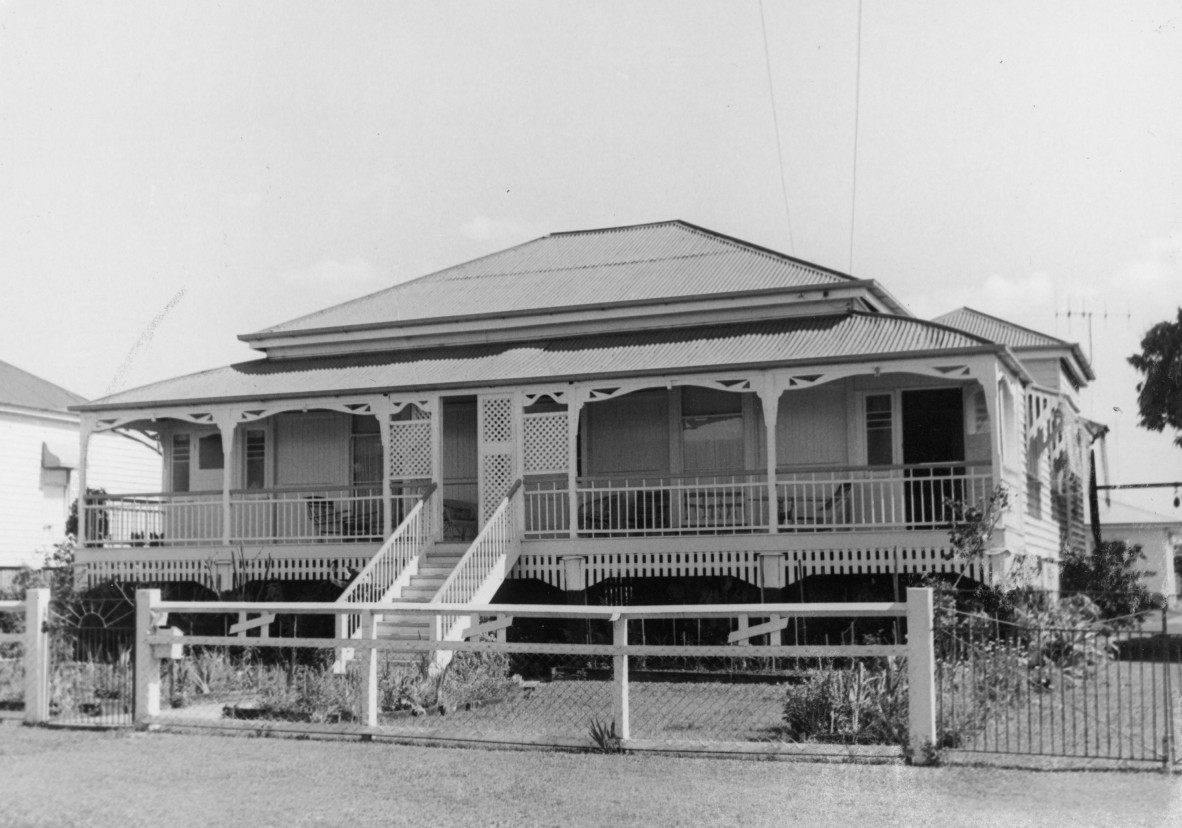 BW image of single storey weatherboard house with a corrugated iron roof and a chain link and timber fence at Maryborough