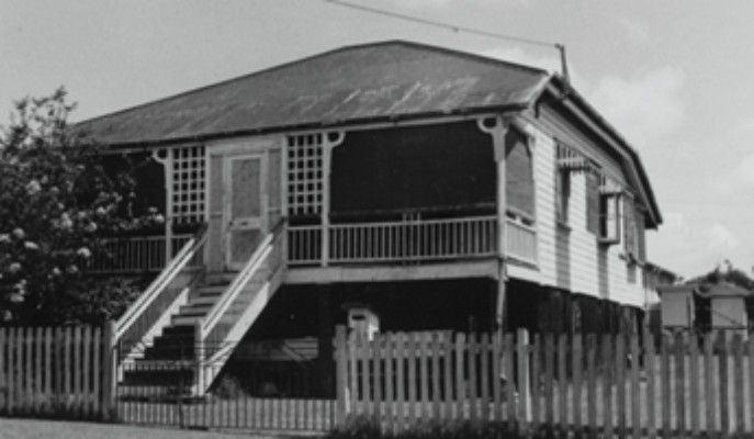 A weatherboard house with stairs at the front and a tree at the side
