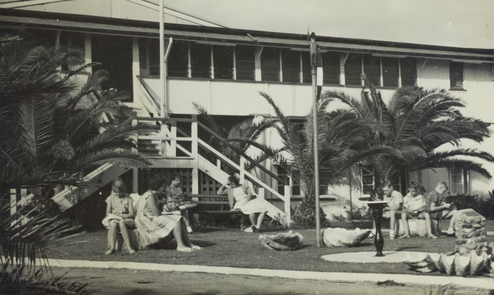 Children attending a Children's Camp sitting reading at the front of the main building of the Alexandra Park Camp.