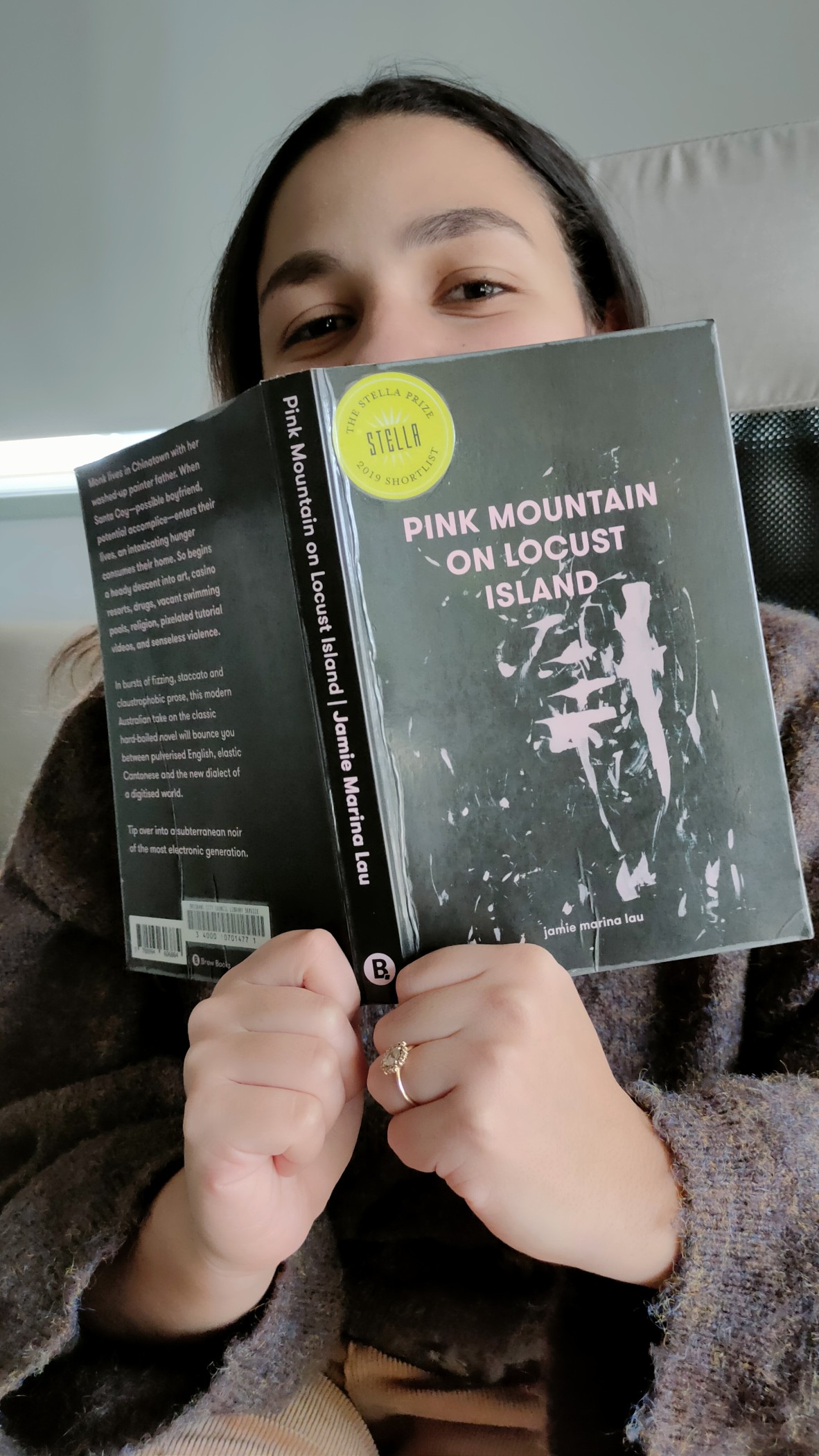 Sara El Sayed holds a copy of Pink Mountain on Locust Island by Jamie Marina Lau
