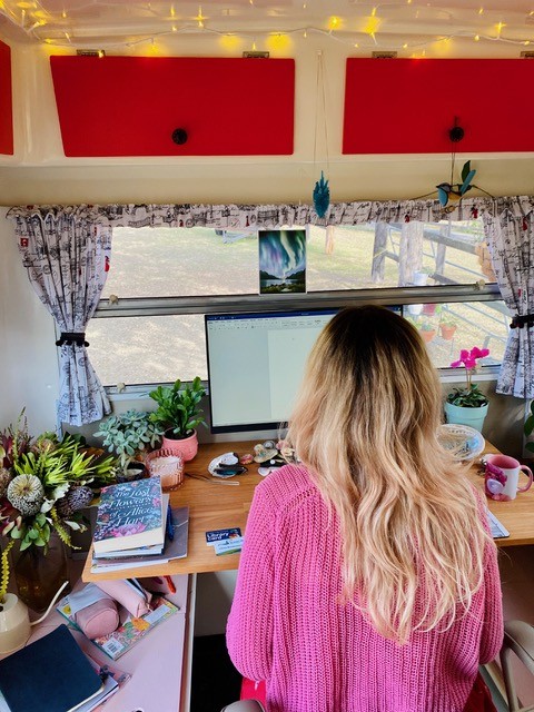 A woman sitting in front of a computer screen with her back to the viewer.