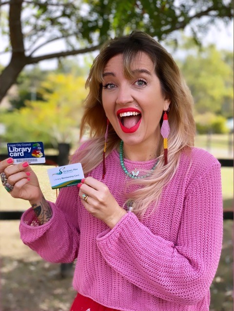 A woman with an open-mouthed smile holding a library card in each hand.