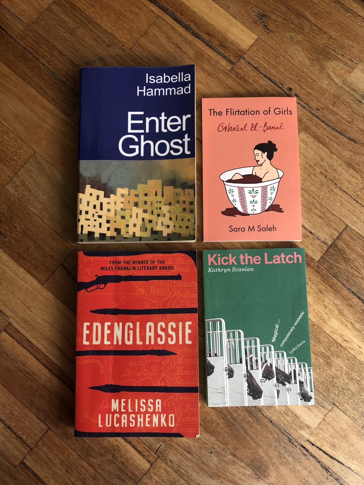 Four books on a wooden background: Enter Ghost, The Flirtation of Girls, Edenglassie and Kick the Latch