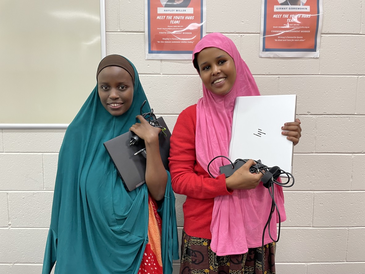 Two young women holding laptop computers