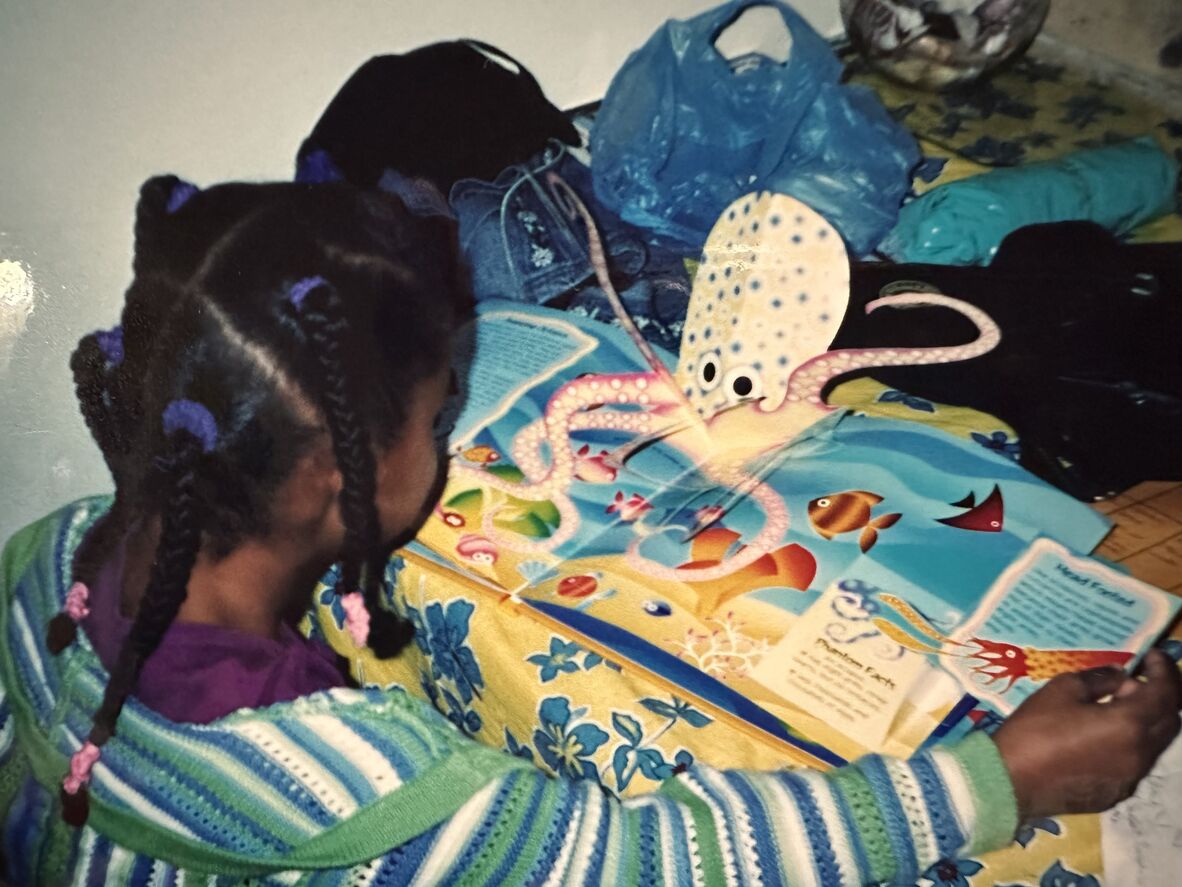 A girl in plaits and a bright jumper reads a book about sea creatures, including a pop-up octopus