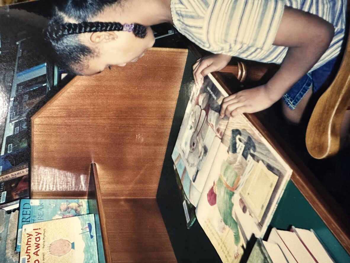 A girl in plaits sits at a desk reading a book