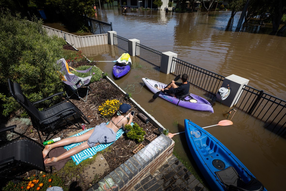 People in flooded waters on paddle boats and sunbathing