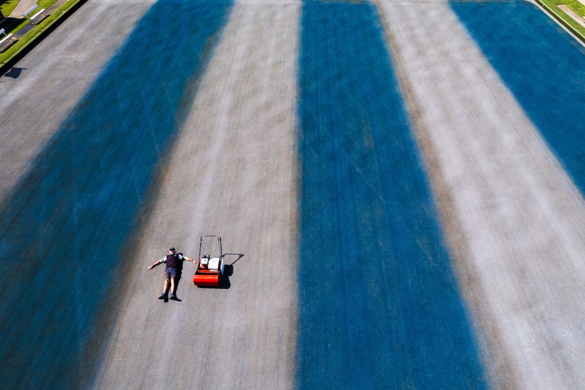 Photo of a man lying in a field painted in large blue and white stripes