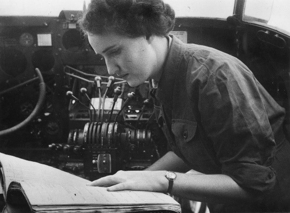 A woman in the cockpit of an aeroplane looking at a book