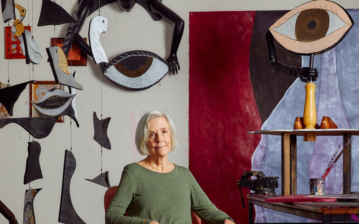 woman sitting in art studio with abstract eye shapes in background