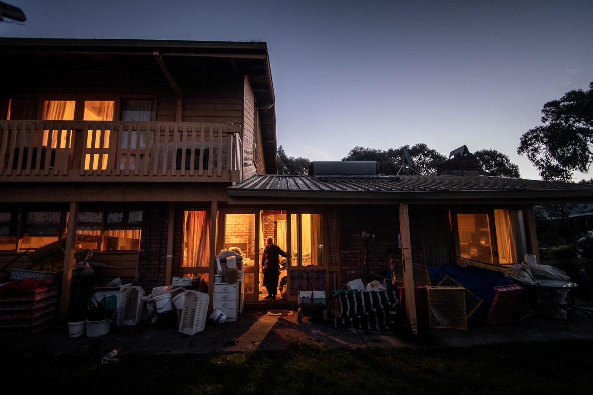 A photo of a house at dusk with a woman in the doorway