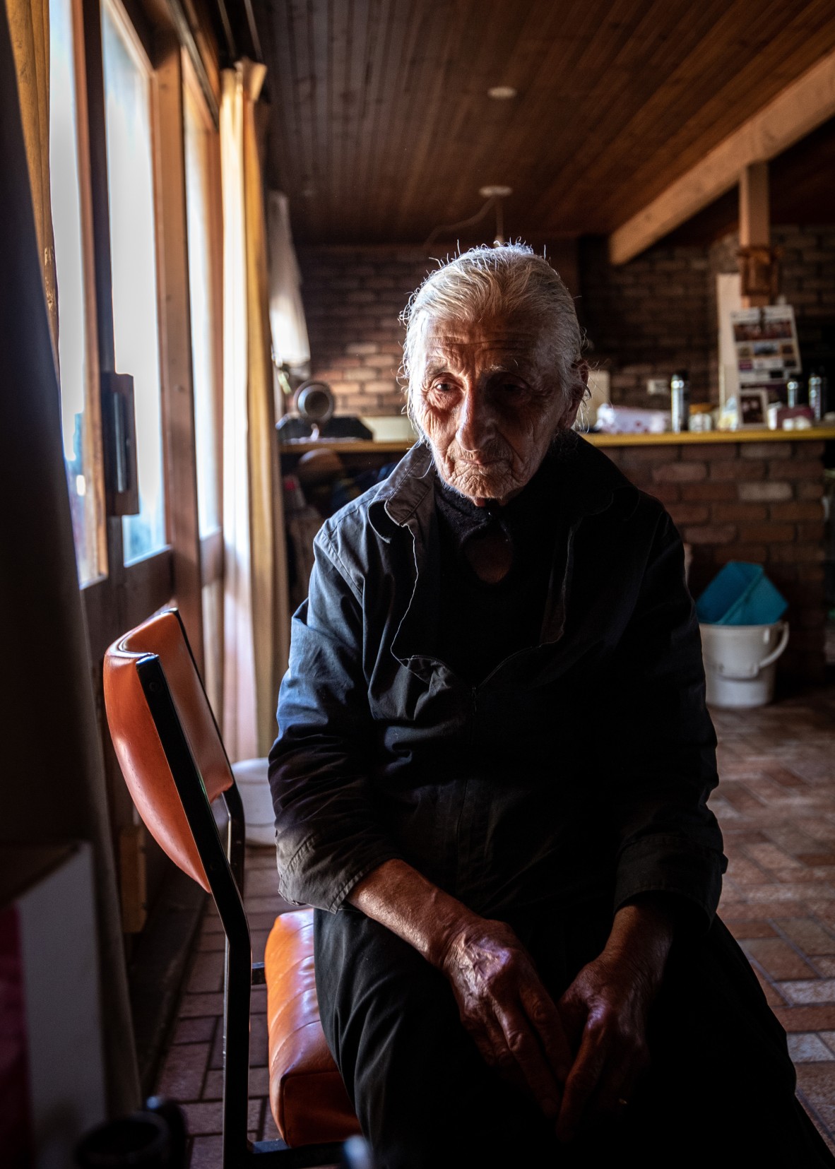 An image of an elderly woman sitting in a chair grieving