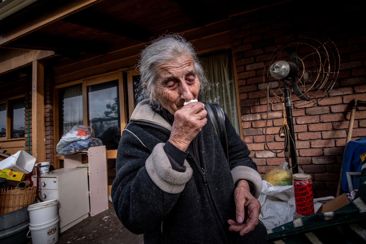 A photo of an elderly woman crying as she leaves her home