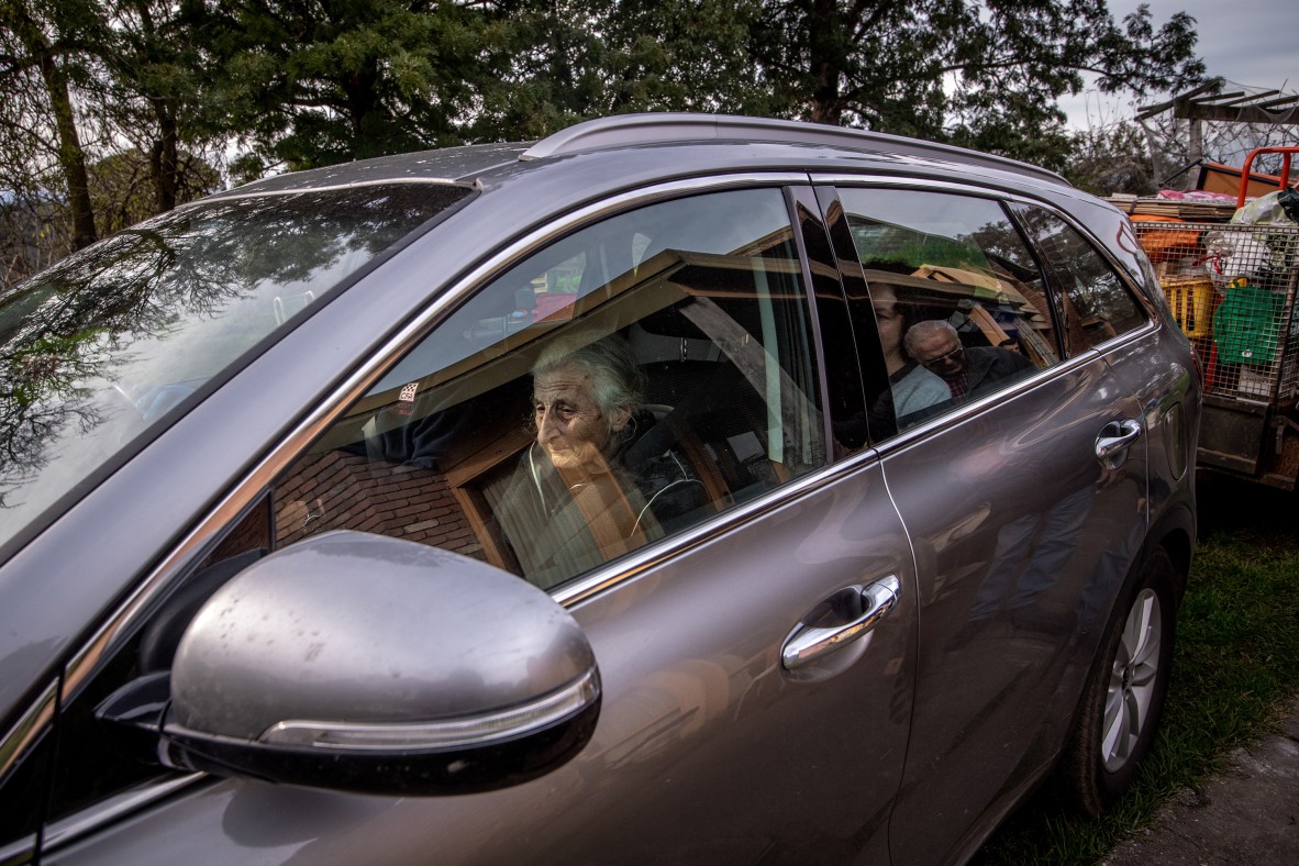 A photo of an car with an elderly woman in the passenger seat