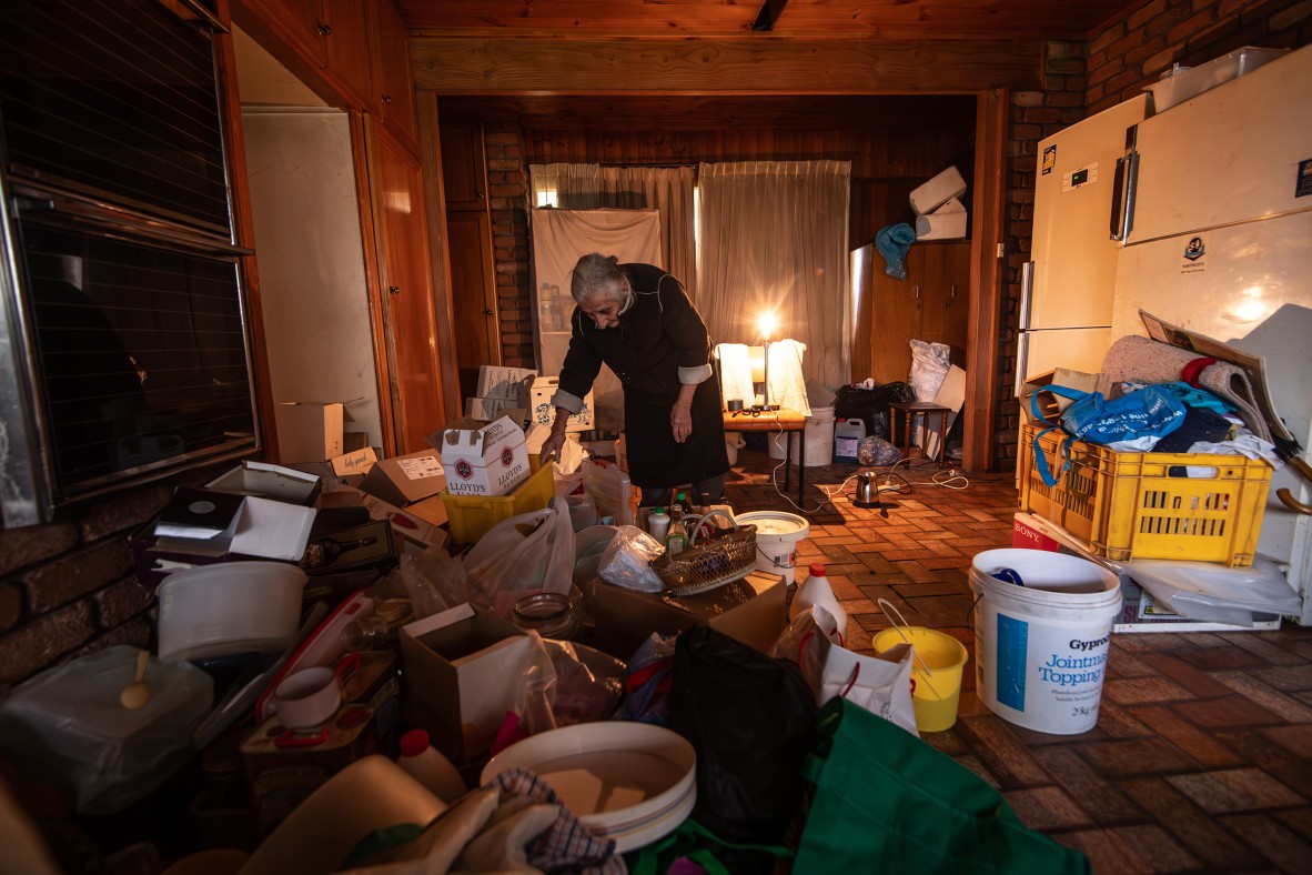 A photo of an elderly lady packing up a room filled with lots of stuff