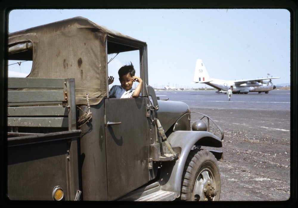 A Vietnamese kid sitting inside a military car near the airfield, Vietnam, 1968-69.