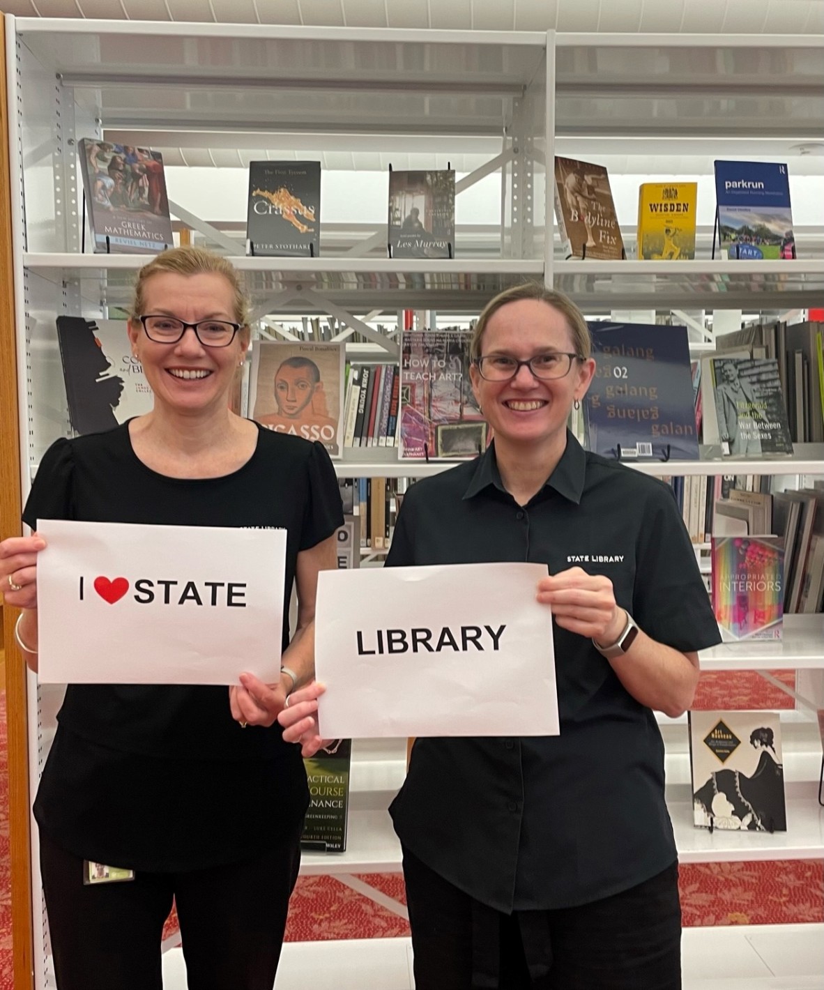 Two library staff members holding an I love State Library sign
