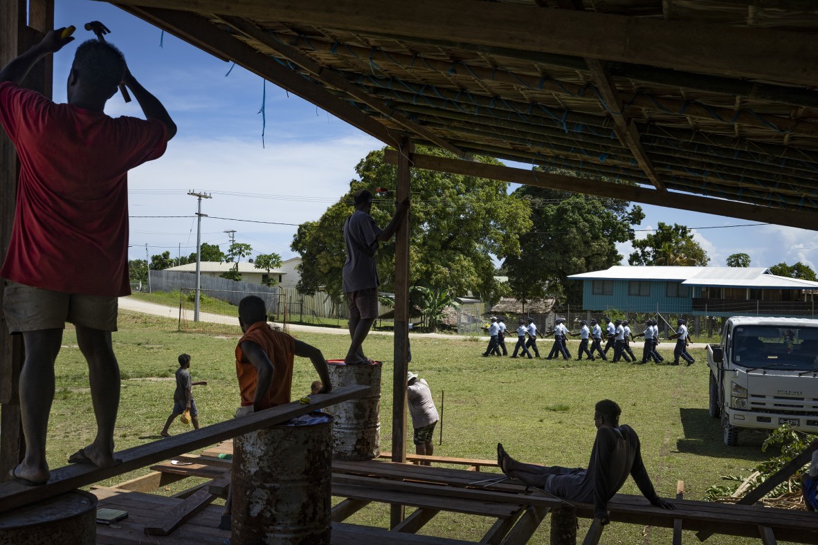 A photo of a group of young men gather to watch and practise for a dance competition outside a destroyed building in Honiara’s Chinatown