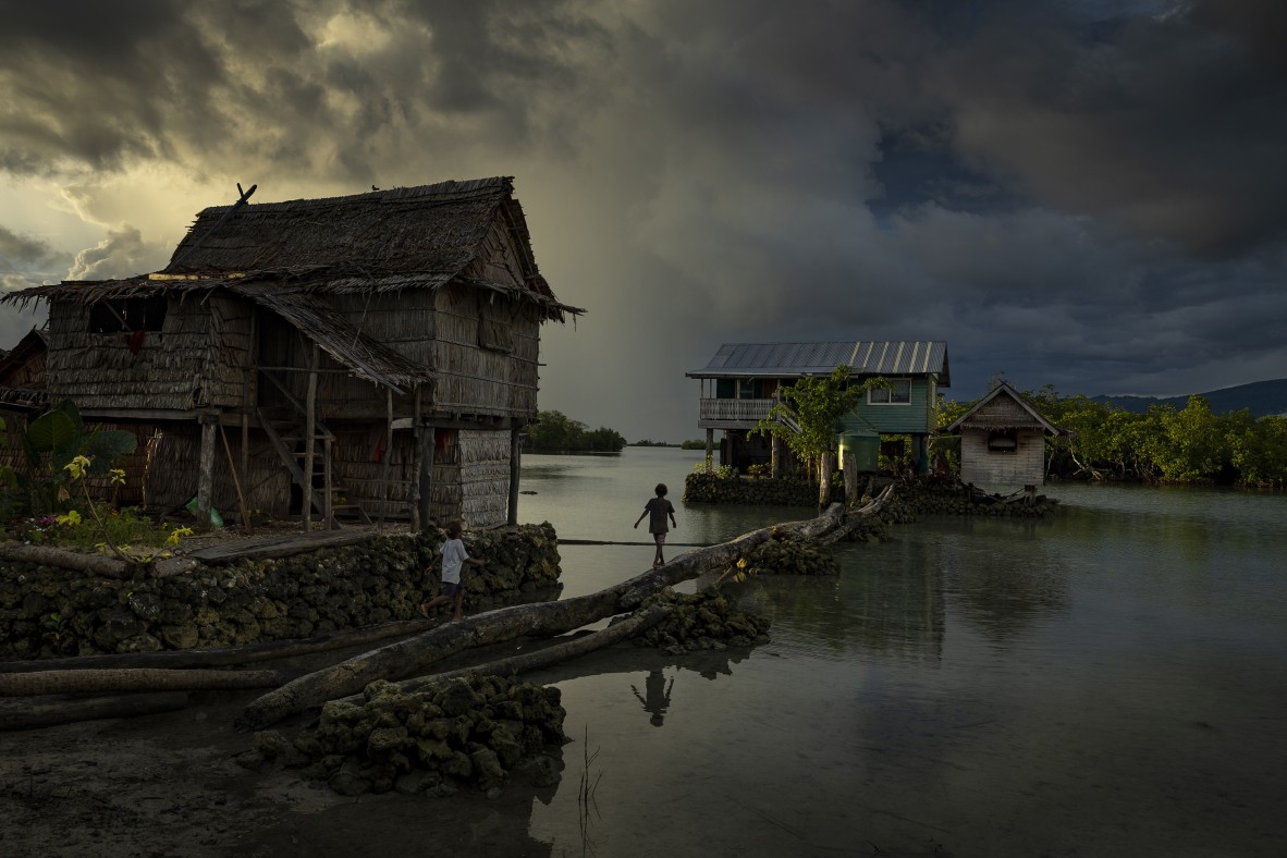 A photo of children walking between houses along man-made walkways on Buloabu, an artificial island