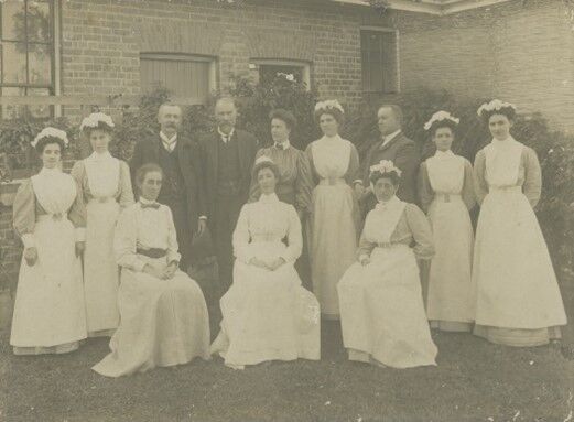 A group of medical professionals in formal dress standing outside the Lady Lamington Hospital building