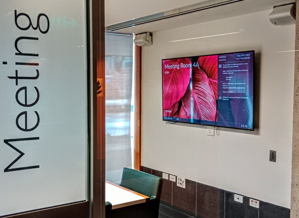 Image of a flat screen in a meeting room seen from the glass wall.