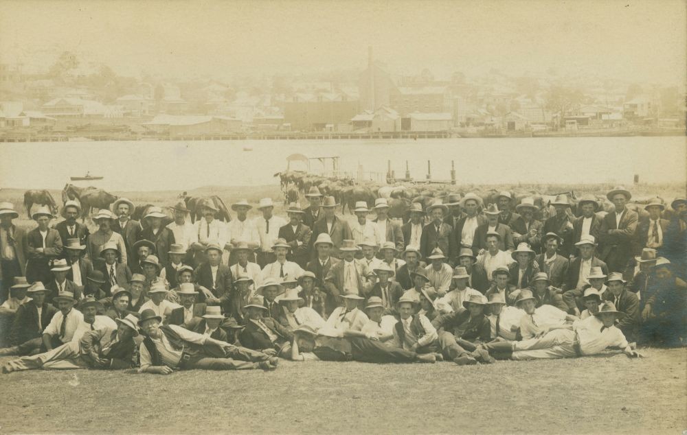 Large group of men sitting and standing with Brisbane River in background, 1912.