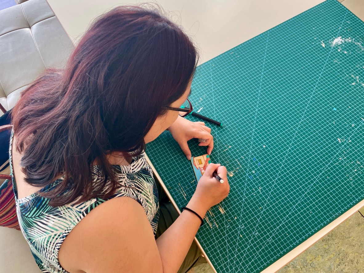 a person painting a laser cut mini queenslander with paint pens