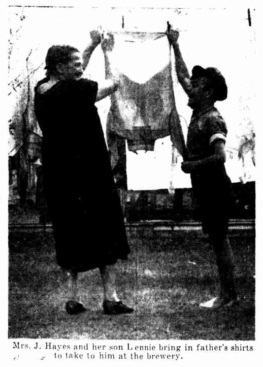 Black and white photo from a newspaper of a woman and young boy hanging a shirt on a washing line. Caption reads: 'Mrs. J. Hayes and her son Lennie bring in father's shirts to take to him at the brewery'.