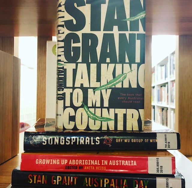 A pile of books by First Nations authors sitting on a shelf