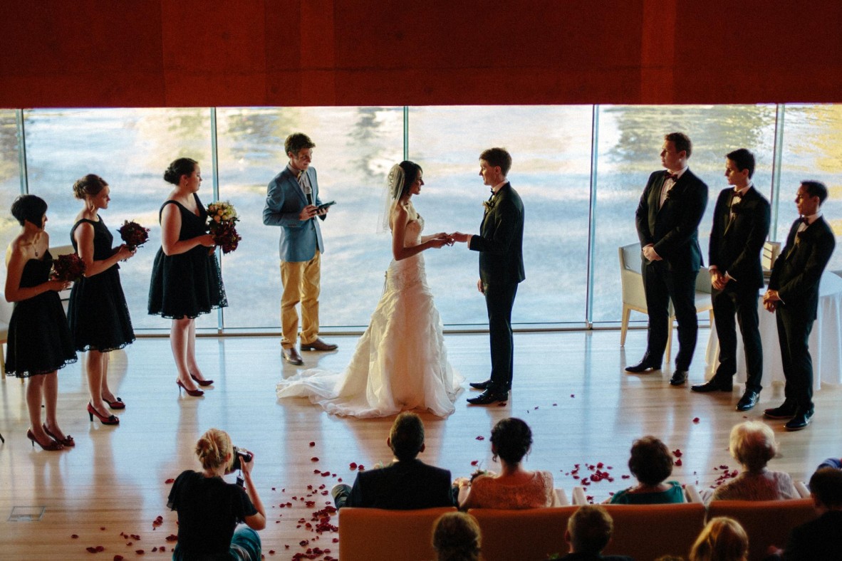 Wedding party standing during the ceremony with the river in the background, as guests watch from their seats.