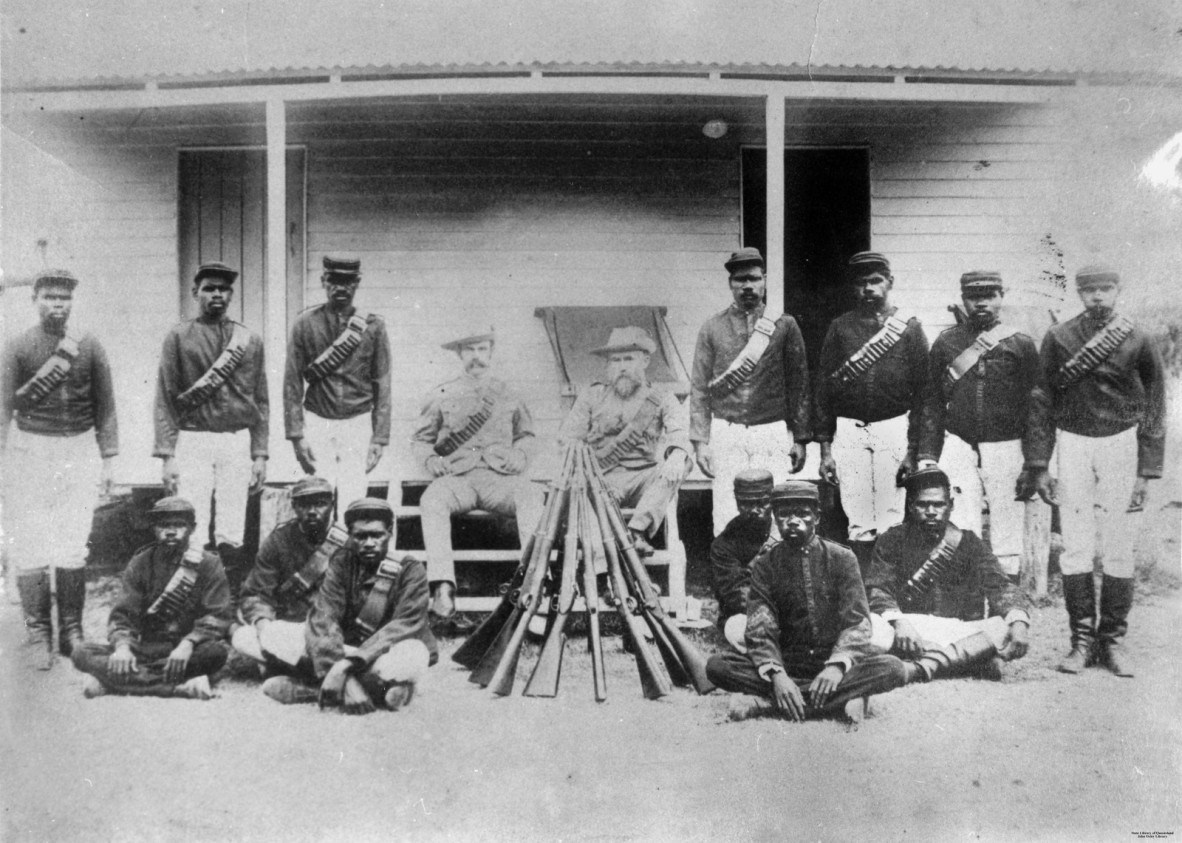 First Nations Native Police and officers in front of a wooden building