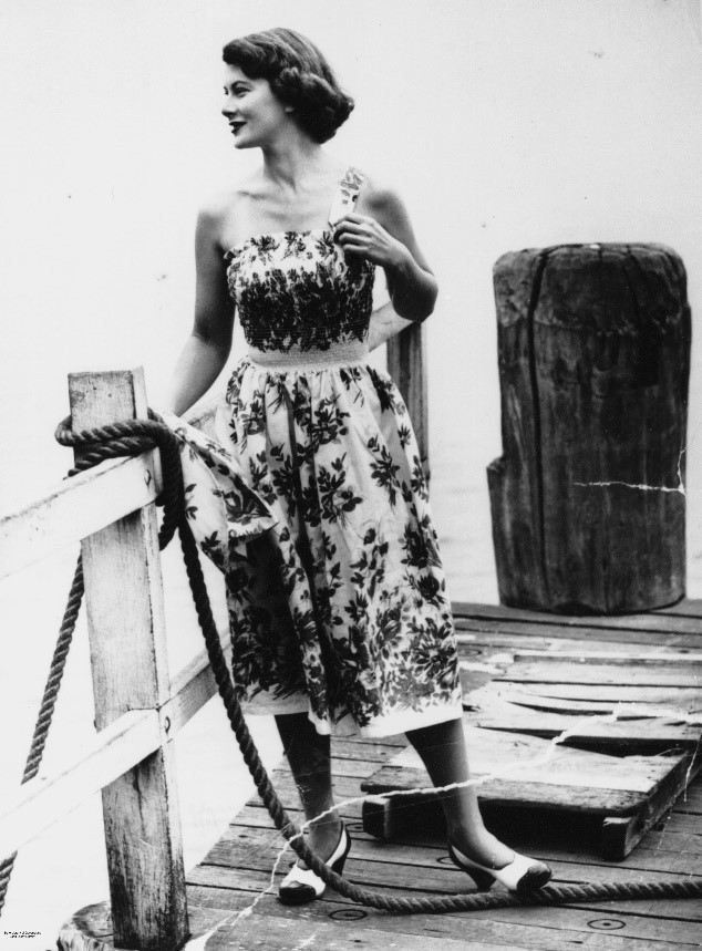 A picture of a woman wearing a dress and standing on a jetty