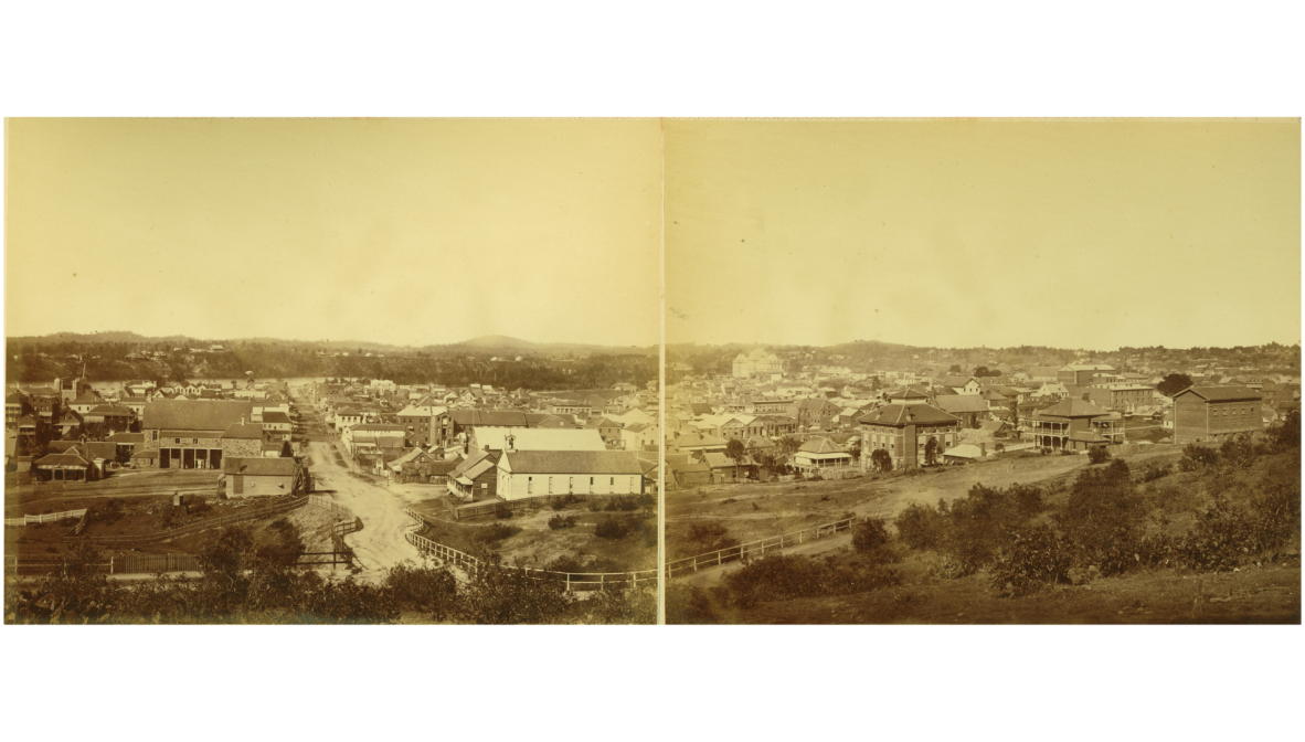 A panoramic photograph comprised of two photos joined together, show from Wickham Terrace in 1875. Kangaroo Point cliffs can be seen in the distance, and some prominent Brisbane buildings emerge in the skyline alongside houses and scrub.