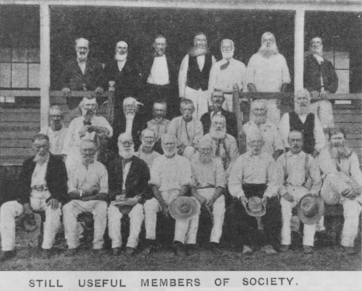 Black and white photo of 4 rows of men on verandah and steps with the caption "Still useful members of society"